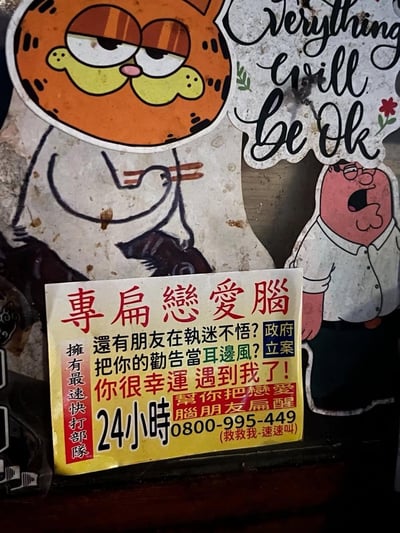 图片展示了一个带有幽默讽刺意味的拼贴作品，主要包含三个元素：左侧是卡通角色加菲猫，它表情冷漠，眼神向下看；右侧是另一个卡通人物乔恩·艾伯克，他张大嘴巴，表情惊讶；中间偏下位置有一张黄色背景的红色文字告示，内容是关于