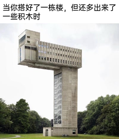 这是一张经过P图改编的趣味梗图，图中展示了一栋造型怪异的T字形混凝土建筑，主体立柱上方横向延伸出大面积的带窗楼层，左侧还额外拼接出一个小型建筑模块，整体外观极不符合常规建筑逻辑，像是搭积木时将剩余材料随意附加的产物。图上方配有文字“当你搭好了一栋楼，但还多出来了一些积木时”，用生活化的场景幽默调侃这栋建筑的奇特设计，让观者产生共鸣，感受到荒诞的趣味。