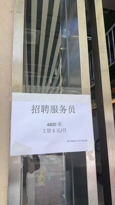 一张贴在玻璃门上的招聘启事，内容显示某火锅店招聘4800名服务员，月薪却仅为5元。这种极低的薪资与大量招聘人数形成鲜明反差，显得非常荒谬和不现实，可能是商家为吸引眼球而制作的搞笑内容。