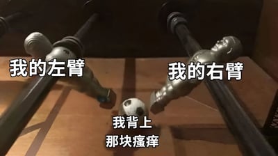 图片展示了一张桌上足球台的特写，左右两侧的金属球员人偶分别被标注'我的左臂'和'我的右臂'，中间的足球下方配有文字'我背上那块瘙痒'。通过桌上足球球员无法触及中间足球的场景，幽默地比喻了人们想用左右手抓后背瘙痒却够不着的无奈日常。