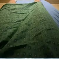 这是一张原始拍摄的日常家居照片，画面主体是一块带有重复浅色圆形图案的深绿色柔软布料，随意铺展在蓝色床品表面，记录了普通的家居场景，没有包含双关、谐音梗或其他暗示内容，整体风格平淡日常。