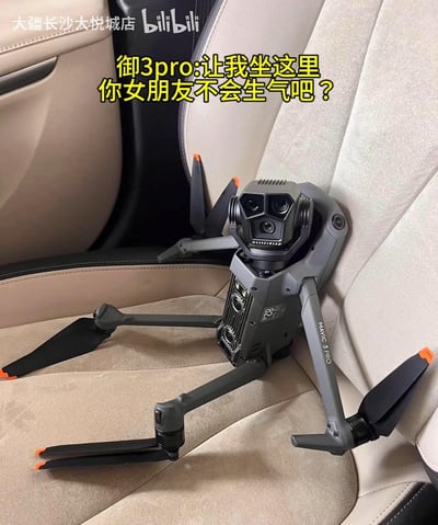这张图将大疆Mavic 3 Pro无人机放置在汽车座椅的角落，模仿网络上流行的“绿茶语录”句式，配上文字“御3pro:让我坐这里你女朋友不会生气吧？”，把无人机拟人化，制造出设备在和用户“争宠”的搞笑反差，调侃无人机爱好者对设备的喜爱，用趣味的方式进行产品宣传。
这个梗源自网络上的绿茶话术“哥哥，我坐你副驾你女朋友不会生气吧”，属于对经典梗的二次创作。