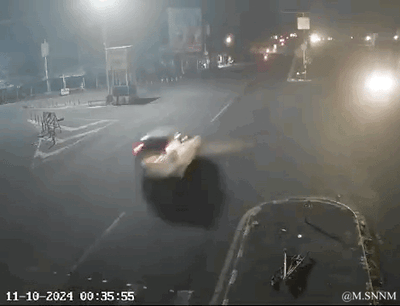 这是一段记录夜晚路口交通事故瞬间的动态GIF，画面显示2024年10月11日00:35:55，一辆轿车在路口处失控，车身出现倾斜，似乎刚发生碰撞，画面右下角有一辆倒地的电动车，场景为灯光昏暗的城市路口，整体氛围紧张惊险，还原了突发交通事故的瞬间。