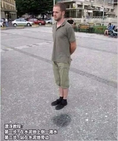 这是一张利用拍摄角度制造视觉错觉的搞笑梗图，画面主体为一名身穿军绿色短袖POLO衫、卡其色七分裤的白人男子，站在城市户外公共广场的水泥地面旁，男子双手背在身后，表情平静。由于拍摄角度刚好让他的脚和脚下地面上的一滩水的倒影重合，视觉上看起来仿佛他双脚悬空漂浮在半空中。图片左下角配有白色文字的搞笑“漂浮教程”，调侃了这种利用视觉错位制造漂浮假象的小技巧，趣味十足。