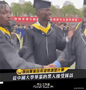 这是一段GIF动态图，画面中几名身着中国大学学士服的黑人毕业生正在欢快互动，氛围轻松喜悦。背景的红色横幅上写有中文标语“怀抱梦想又脚踏实地 敢想敢为又善作善成”，图下方配有繁体中文字幕“順利畢業你希望感謝是什麼 從中國大學畢業的黑人接受採訪”，记录了外国留学生在中国完成学业、顺利毕业的温馨场景。