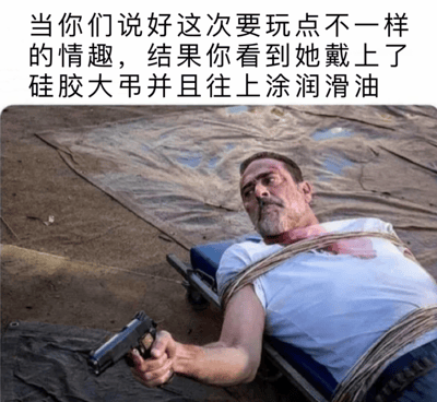 这是一张搞笑梗图，图上方配有文字“当你们说好这次要玩点不一样的情趣，结果你看到她戴上了硅胶大弔并且往上涂润滑油”，下方是美剧《行尸走肉》里的角色尼根被绳索捆绑在担架上的画面，他颈部带有血迹，手持手枪，表情惊恐又带着绝望与不甘。这张图用影视里人物陷入绝境的画面，夸张地表现出情侣尝试特殊情趣时，看到超出预想的场景后那种恐惧、无力又尴尬的心情，通过荒诞的反差制造出喜剧效果。