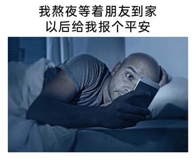 这是一张图文结合的网络梗图，上方配有文字“我熬夜等着朋友到家以后给我报个平安”，下方的图片呈现出深夜卧室的场景，整体色调偏冷蓝色，一名光头男子趴在床上，盖着被子，一只手撑住头部，另一只手举着手机，眼神专注地凝视着手机屏幕，神情中带着熬夜的疲惫却依旧坚持等候，生动地传递出对朋友的牵挂与在意，即使自己处于困倦的状态，也坚持要等对方到家报平安才安心的情绪。