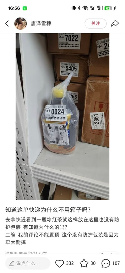 这是一张社交媒体帖子截图，画面展示了快递站的货架上，一瓶冰红茶没有使用纸箱等防护包装，仅在瓶身外包裹透明塑料并直接粘贴快递面单摆放，周围都是常规的纸箱包装快递；发帖人起初提问为何这件快递不用箱子，后续补充说明评论区给出的玩梗答案“牢大耐摔”，该内容因强烈的反差感和结合网络热梗引发趣味讨论。