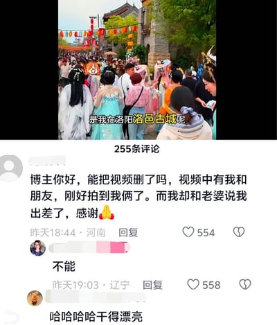这张图是国内短视频平台的页面截图，上半部分是洛阳洛邑古城的实拍视频画面，古街悬挂着彩色灯笼，大量游客聚集游玩，其中不少人身着汉服，画面配文显示拍摄者身处洛阳洛邑古城；下半部分是该视频的评论区，共有255条评论，最高赞的评论来自IP属地河南的网友，称自己和朋友被拍进了这条视频，而他此前跟老婆谎称自己在出差，恳求博主删除视频并附上合十表情，博主直接回复了“不能”，该回复也收获了550+的高赞，另有其他网友评论“哈哈哈哈干得漂亮”，整个内容充满了撒谎被抓包又求助无门的搞笑社死反差感。