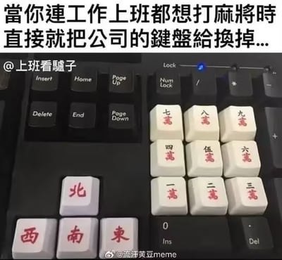 图片展示了一个被改造的电脑键盘，部分标准键帽被替换成了麻将牌造型的键帽，包括“一万”“二万”“三万”“四万”“五万”“六万”“七万”“八万”“九万”以及“东”“南”“西”“北”等麻将牌面。键盘上方配有文字“當你連工作上班都想打麻將時 直接就把公司的鍵盤給換掉...”，幽默地表达了上班族在工作时因沉迷打麻将而将办公键盘改造的搞笑场景，展现了职场摸鱼文化与麻将爱好的趣味结合。
