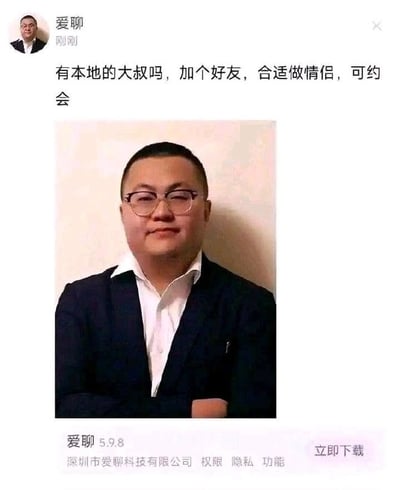 这是一张交友软件爱聊的引流广告截图，发布账号昵称为“爱聊”，配文为招募本地大叔交友、发展情侣关系甚至约会的内容，但配图却是一位戴眼镜、穿深色外套配白衬衫的中年男士本人，文案和配图形成强烈反差，充满恶搞感，截图底部还标注了爱聊APP的版本号、开发主体信息以及立即下载的引导按钮，属于典型的为吸引流量制作的搞怪钓鱼类广告素材。