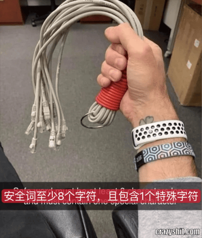 图片展示了一只手握着一大捆缠绕混乱的灰色网线，线的末端有多个水晶头。手的主人戴着两个手环，手腕上有纹身。图片底部有一条红色横幅，上面写着“安全词至少8个字符，且包含1个特殊字符”。

这张图用缠绕混乱的网线形象地比喻了设置复杂密码时的困扰和无奈，通过视觉上的混乱感来幽默表现人们面对复杂安全要求时的感受。