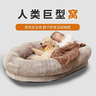 图片展示了一个被称为“人类巨型窝”的大型圆形灰色毛绒床，内部有一只金毛犬和一名儿童共同躺卧。金毛犬表情愉悦，吐着舌头，前爪自然抬起；儿童头部部分可见，身着白色衣物，被棕色毯子覆盖。上方文字标题为“人类巨型窝”（其中“窝”字为橙色），下方橙色按钮内文字为“更有安全感 躺下即享深度睡眠”，整体营造出舒适、安全的睡眠氛围，暗示该产品能提供类似宠物窝的安全感和深度睡眠体验。