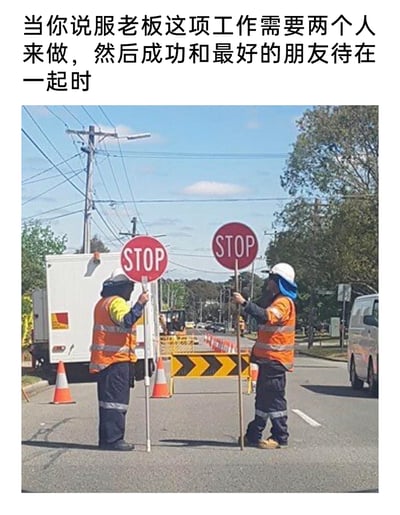 这是一张充满趣味的职场梗图，图片上方配有中文调侃文案，图中呈现的是国外真实道路施工现场：两名穿着反光安全背心、戴着安全帽的工作人员并排站在道路上，各自举着一块写有“STOP”的停车牌，从场景来看这项指挥工作单人即可完成。文案和画面结合，用来调侃职场中打工人为了能和好友共事，故意将单人可完成的工作申请为双人岗位的有趣小心思，精准戳中打工人想和好友一起上班的小愿望，充满共鸣感。