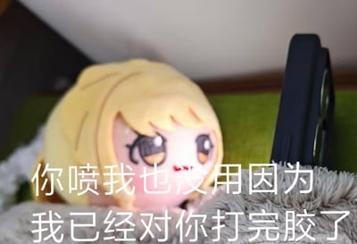 这是一张文字加注类卡通表情包，图中的金发卡通玩偶露出得意傲娇的表情，趴在毛绒织物上，配文“你喷我也没用因为我已经对你打完胶了”。这里的“打胶”是玩梗，用“木已成舟无法改变”的耍赖态度，回应他人的吐槽或指责，传递出一种摆烂又得意的搞怪情绪，适合在和朋友抬杠、被吐槽时使用。
