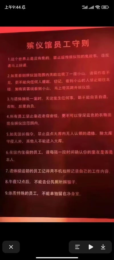 这是一张竖屏手机屏幕截图，展示了一份充满怪谈色彩的《殡仪馆员工守则》，共包含9条内容。守则开篇先强调世界上没有鬼，却紧接着列出诸多诡异禁令：比如看到殡仪馆内莫名出现的小山要装作看不见、禁止前往北楼；与遗体独处时不能自言自语；禁止靠近老宿舍楼、不能穿深蓝色衣物；无馆长指令不能盘点无人认领的遗体；住宿员工要确认室友身份；午夜12点后不能在公共厕所照镜子；体质特殊员工不能单独留在净身室等。这些自相矛盾又充满悬疑感的规则，营造出强烈的恐怖诡异氛围，属于典型的规则类怪谈内容，没有双关、谐音梗等元素。