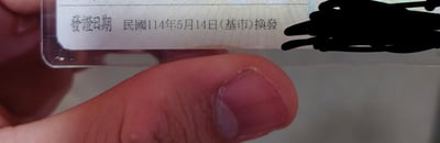这张图片显示了一张证件卡片的局部特写，证件右下角明确标注“发证日期 民国114年5月14日（基市）换发”。民国纪年通常用于台湾，民国114年对应公历2025年。这类图片常见于展示台湾身份证、驾照等官方证件更新时，部分敏感信息被打码处理。图片左下角有手指夹持证件，是拍摄此类照片的常见姿势。

图片本身没有明显双关、谐音梗或暗示内容，主题正经，但用民国纪年会让少数外地网友感到迷惑或产生时空错乱的玩笑氛围。