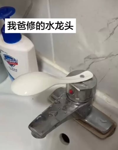 这是一张实拍的洗手台场景照片，台面上的金属水龙头原本的开关把手损坏，发布者的父亲没有更换专业配件，而是用一个普通的白色塑料饭勺，通过螺丝固定在水龙头的开关位置，替代原有把手来控制水流，旁边还摆放着舒肤佳的洗护用品，图片上方配文“我爸修的水龙头”，充满生活里接地气的脑洞趣味，体现了长辈维修时讲究实用、奇思妙想的特点。