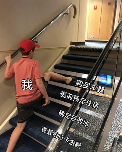 这是一张利用视觉错位创作的搞笑调侃梗图，图中一名反戴红色鸭舌帽、穿红色短袖黑色短裤的男孩背对镜头攀爬楼梯，右侧玻璃扶手反射了男孩腿部，形成了男孩长了三条腿，无法顺利迈过下一级台阶的错觉。图中添加了文字标注：男孩后背标注为“我”，从靠近镜头到上方的台阶依次标注“查看银行卡余额”“确定目的地”“提前预定住宿”“购买车票”，错位效果让男孩的腿刚好卡在“查看银行卡余额”这一级台阶，调侃了普通人计划旅行时，做好了全部准备工作，最终却因为银行卡余额不足，无法成行的尴尬处境，幽默地表现了想旅行却没钱的现状。