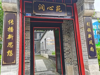 这是一张实地拍摄的中式传统门脸照片，拍摄地点为按察司街68号的润心苑。门楣上方悬挂黑底金字牌匾，上书“润心苑”；门两侧配有竖幅黑底金字标语，左侧为“传播新思想”，右侧为“引领新风尚”。透过门洞可见内部青砖灰瓦的传统院落建筑，墙面挂有“实践站”“服务工作站”“服务站”“民意联络站”的标识牌，整体风格古雅庄重，是一处承担文化传播与社区服务功能的场所。