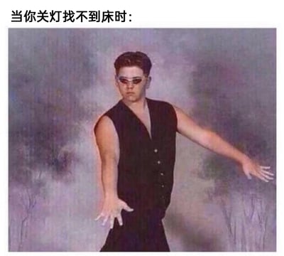 这是一张用来调侃日常趣事的梗图，图上方配有文字“当你关灯找不到床时:”，图中是一位穿着黑色无袖上衣、戴着窄框墨镜的男子，他双臂向身体两侧张开，双手呈张开摸索的姿势，表情严肃一本正经，这个姿势精准还原了人们在关灯后身处黑暗环境，找不到床时只能靠双手向前摸索、试探前进的状态，用夸张又贴合的方式将这个日常场景变得搞笑有趣，引发人们的共鸣。
