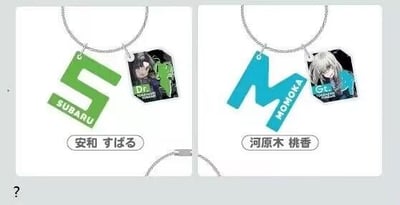 这是一张左右对比的多图拼接静态图，展示了两款《偶像大师 闪耀色彩》的角色主题钥匙扣。左侧钥匙扣搭配绿色大写字母“S”吊牌与印有角色安和昴形象的方形吊牌，字母吊牌下方印有英文“SUBARU”，底部标注日文“安和 すばる”；右侧钥匙扣搭配蓝色大写字母“M”吊牌与印有角色河原木桃香形象的方形吊牌，字母吊牌下方印有英文“MOMOKA”，底部标注日文“河原木 桃香”。两款钥匙扣均采用钢缆绳作为挂绳，整体为卡通风格的周边产品宣传图。