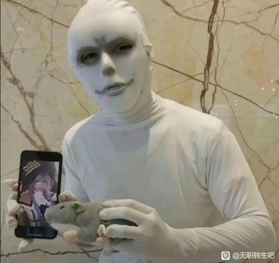 图中是一位cos《无职转生》里“人神”的爱好者，全身穿着白色紧身衣模仿人神的诡异形象，一只手拿着显示洛琪希（《无职转生》人气角色）照片的手机，另一只手抱着仓鼠玩偶，以此还原原作里人神通过老鼠给鲁迪传递信息、引导鲁迪的经典情节，玩了原作的核心梗，风格搞笑恶搞。