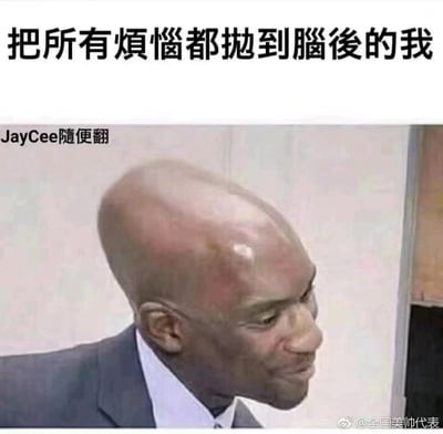 这是一张搞笑类网络表情包，上方配有文字“把所有烦恼都抛到脑后的我”，图中是经过P图修改的光头黑人男性，他穿着西装，头部向后仰，面带略带勉强的微笑。图片利用光头的造型和配文形成双关梗：既字面表达将烦恼从脑海中抛开的心情，又用光头的形象调侃“脑子里空无一物，没有烦恼”，整体风格幽默诙谐，常用于表达想要摆脱烦恼、放空自我的情绪。