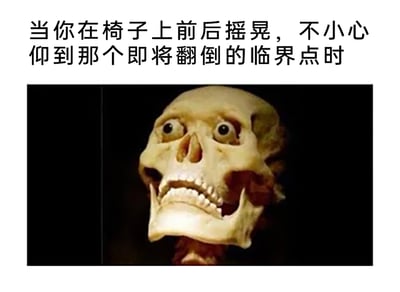 这是一张贴合日常体验的趣味梗图，上方配有文字“当你在椅子上前后摇晃，不小心仰到那个即将翻倒的临界点时”，精准描述了一个很多人都经历过的惊险小场景；下方是经过拟人化修改的骷髅形象，它被赋予了瞪大的眼睛，嘴巴张开露出牙齿，面部神态极度惊恐紧张，生动地将人在椅子即将后仰翻倒瞬间的恐慌、心脏骤停的情绪具象化，用夸张的视觉效果放大了日常小意外带来的惊吓感，很容易让有过相同经历的人产生共鸣，充满搞笑又真实的氛围。