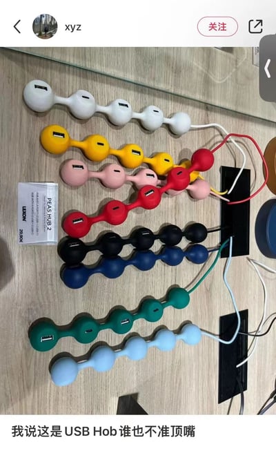 社交媒体截图展示了多款彩色豌豆造型的USB Hub产品（PEAS HUB 2），整齐排列在木质桌面上。产品有白色、黄色、粉色、红色、黑色、蓝色、绿色及浅蓝色共8种配色，每个Hub由多个圆润的“豌豆”串联而成，每个“豌豆”上均有USB接口。左侧有产品标签，标注“PEAS HUB 2”“LEXON”及价格“29.99€”。图片底部配有文字：“我说这是USB Hob谁也不准顶嘴”，语气俏皮有趣。