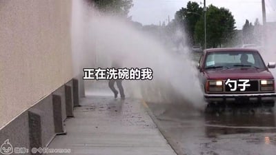图片中一辆红色汽车正在向人行道上的人喷射大量水流，被喷的人狼狈躲闪。画面上方叠加文字“正在洗碗的我”，汽车前方叠加文字“勺子”，通过夸张的喷水场景比喻用勺子洗碗时被大量水冲击的无奈与搞笑情景。左下角有水印“微博：@今日memes”，表明为社交媒体上的搞笑 meme 内容。