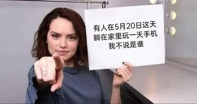 这是一张适合在520节点传播的调侃类梗图，图中人物是演员黛西·雷德利，她表情略带戏谑，眼神看向镜头，带着调侃的意味，一只手举着写有“有人在5月20日这天躺在家里玩一天手机 我不说是谁”的白纸，另一只手伸出食指指向观看者。图中文字用“我不说是谁”的半开玩笑表述，既像是调侃他人，又带有自嘲的意味，精准戳中了不少人在被赋予浪漫含义的520当天，选择宅家玩手机、不参与节日相关外出活动的状态，整体氛围轻松幽默，适合用来表达自己的宅家日常。