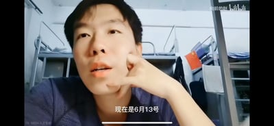 这是B站up主“向前的赵”的vlog视频截图，画面中博主身处大学宿舍的上下铺环境里，用手轻托脸颊，正对着镜头说话，画面下方的字幕标注“现在是6月13号”。背景中可以看到宿舍的双层铁架床铺，还悬挂着一面中国国旗，整体是非常生活化的日常记录场景，没有双关、谐音梗或暗示类内容。