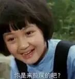 图片展示了电影《囧妈》中的一个经典场景：一位短发小女孩穿着蓝色上衣和黑色背带，面带灿烂微笑，开口说出台词‘你是来拉屎的吧?’。该片段因台词的直白幽默成为网络流行 meme，常被用于轻松调侃的语境中。