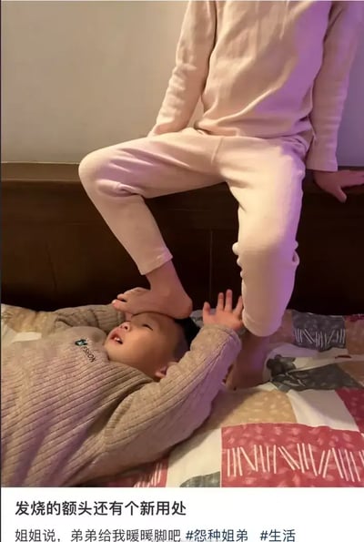 这张图片展现了兄妹之间日常生活中的搞笑瞬间。画面中，躺在床上的男孩头上顶着姐姐的脚，显得有点无奈，配合旁边的文字“一发烧的额头还有个新用处——弟弟给我暖暖脚吧”，突出兄妹之间互怼又充满爱意的关系。这种夸张的场景带有轻微的恶作剧意味，十分贴近中国家庭内部的幽默氛围。

注意：图片配文有明显的双关梗和生活小趣味，将“发烧头烫”与“用来暖脚”相结合，形成反差萌。