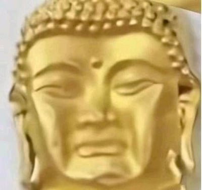 图片为一尊金色佛像头部的特写镜头，佛像双目微闭，面容安详，头顶有明显的肉髻（佛顶骨隆起），面部线条柔和，整体呈现出庄严宁静的气质。佛像表面为光滑的金色材质，细节清晰，展现了佛教造像艺术的典型特征。