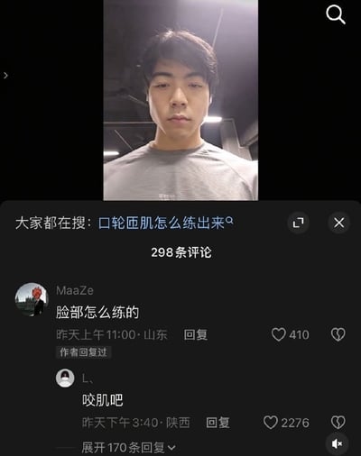 这是一张社交媒体评论区截图，图片上方是一位穿着灰色短袖的年轻男子正对镜头自拍，他的脸部咬肌非常发达、下颌线条十分清晰；下方是社交平台的评论区区域，顶部搜索栏显示热门搜索内容为「口轮匝肌怎么练出来」，标注共有298条评论，评论区中用户MaaZe提问「脸部怎么练的」，该评论获410赞，另一用户L、回复「咬肌吧」，该回复获得2276赞，调侃这名男子突出的脸部肌肉其实是发达的咬肌，内容十分搞笑。