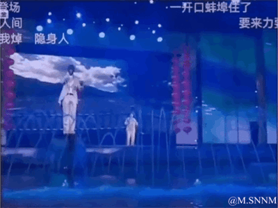这是一张演出直播的画面截图，舞台利用道具与空间设计制造出强烈的视觉错位效果：远处的演员看起来如同巨人一般站在近处演员的头顶上，形成极具反差感的滑稽画面。画面上方的网友弹幕评论如“一开口蚌埠住了”“我焯 隐身人”，进一步放大了这个视觉错觉带来的搞笑氛围，让整个场景充满趣味性。
