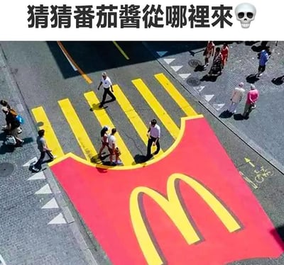 图片上方有黑色文字'猜猜番茄酱从哪里来'并配有骷髅头emoji，下方为航拍视角的创意人行横道照片：红色底色上绘制巨大黄色麦当劳金色拱门标志，多名行人正在此斑马线上行走。通过将麦当劳标志红色部分与番茄酱联想，制造幽默调侃效果。