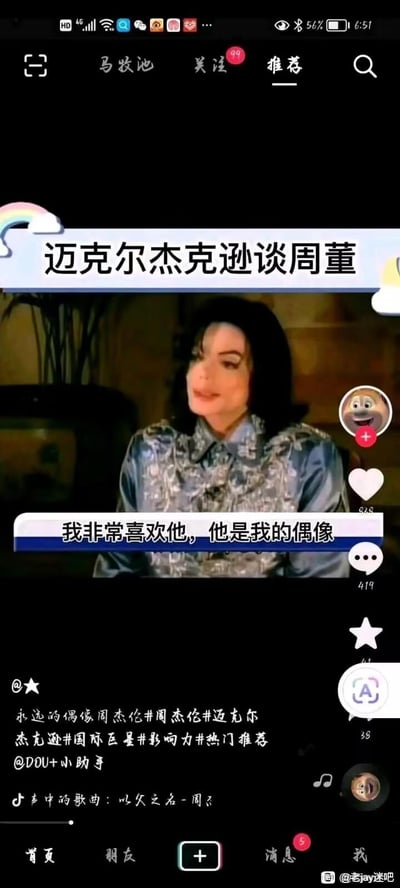 这是一张抖音平台的合成短视频截图，画面截取了迈克尔·杰克逊的真实采访片段，被网友后期添加了虚假字幕“我非常喜欢他，他是我的偶像”，声称迈克尔·杰克逊将周杰伦视为偶像。实际上迈克尔·杰克逊于2009年去世，并未公开表达过此类言论，属于粉丝自制的恶搞玩梗内容，用来调侃或抬高周杰伦的地位。截图中包含抖音的互动按钮（点赞、评论、收藏），下方文案带有关联周杰伦和迈克尔·杰克逊的话题标签，背景音乐为周杰伦的《以父之名》，右下角还有百度贴吧“老jay迷吧”的水印，说明该内容也在粉丝贴吧被传播。