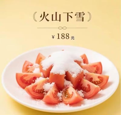 图片展示了一道名为“火山下雪”的菜品，背景为淡黄色。画面中央是一个白色盘子，里面盛放着切片的西红柿，西红柿被摆成中间略高的形状，顶部及表面撒满了白色的白糖，形似火山顶部覆盖着白雪。盘子上方有文字“火山下雪”，下方标注价格“¥188元”。这是一种对简单家常菜（西红柿拌白糖）进行夸张命名和定价的幽默呈现，通过“火山”比喻红色的西红柿堆，“下雪”比喻撒在上面的白糖，形成有趣的视觉和语义关联。