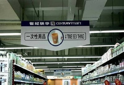世纪联华超市内悬挂的指示牌，上方为品牌名“世纪联华 CENTURYMART”，中间中文“一次性用品”配有一个纸杯图标，下方英文误译为“A TIME SEX THING”（正确应为“Disposable Items”）。背景可见超市货架和天花板灯光，整体场景为超市内部商品区域指引。

图片中的英文翻译存在明显错误，“一次性用品”错译为具有歧义的“A TIME SEX THING”，可能是由于机器翻译或人工校对失误导致，形成搞笑的翻译乌龙。