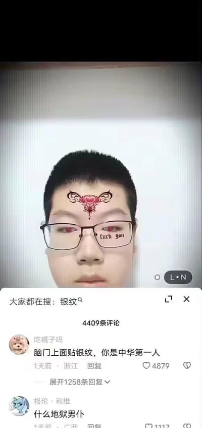 这是一张来自抖音平台的社交媒体截图，画面主体是一位佩戴黑框眼镜的男生自拍，他的额头被添加了带有爱心元素的华丽古风妆容贴纸（对应搜索热词“银纹”），眼镜镜片上还被P上了英文“fuck you”的文字，同时眼睛有变红的特效，整体呈现出强烈的违和反差感。截图下方是评论区，显示共有4409条评论，顶部搜索栏标注“大家都在搜：银纹”，热门评论包括“脑门上面贴银纹，你是中华第一人”“什么地狱男仆”，高赞评论收获了数千点赞，评论区网友纷纷玩梗，调侃这种违和的妆容搭配，整体氛围搞笑猎奇。