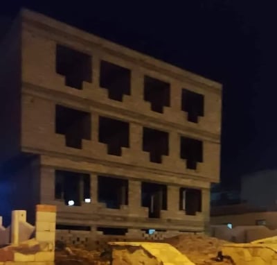 图片展示了一栋夜晚下的在建砖楼，窗户的造型极为方正，酷似《Minecraft》游戏中的方块窗口，营造出现实与像素世界交融的错视感。没有明显双关或谐音梗，但整体风格有魔性和幽默感，令人怀疑现实是否被“像素化”。这种建筑设计常被网友调侃为“游戏场景穿越现实”。