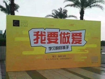 这是一张户外拍摄的宣传板照片，宣传板主体为黄色，上方用醒目的大字号写着“我要做爱”，下方用小字号补充“学习的好孩子”，利用断句制造歧义，完整语义为“我要做爱学习的好孩子”，但第一眼容易被误导产生不当联想，以此制造搞笑效果。宣传板上还标注有“厦门·福州分社”、“HUNDUN UNIVERSITY”字样，左上角有混沌大学的标识，背景可见几棵棕榈树。