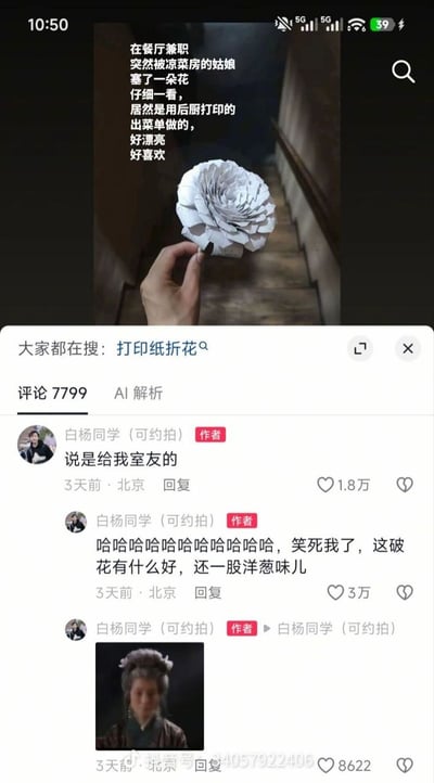 这张图是社交媒体帖子的截图，上半部分为发帖内容：配文称自己在餐厅兼职时被凉菜房的姑娘塞了一朵花，仔细查看后发现花是用后厨打印的出菜单折制而成，造型精致好看，自己很喜欢，配图是一只手捏着这朵白色的纸花，背景为木质楼梯；下半部分是帖子的评论区，发帖人“白杨同学（可约拍）”先后发布三条回复，首先补充说明这朵花其实是姑娘送给自己室友的，随后自嘲吐槽这朵花没什么特别，还带有一股洋葱味，最后配了一张古装老年女性面露无语神态的表情包，该帖累计有7799条评论，作者的几条回复获得了数千到数万不等的点赞，页面还显示相关搜索词为“打印纸折花”。