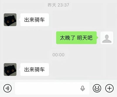 这是一张微信聊天界面的静态截图，聊天记录显示：头像是黑猫的用户在前一天23:37向对方发出“出来骑车”的邀约，对方回复称时间太晚，约定明天再去。结果到了零点整（刚好进入次日），该黑猫头像的用户再次发来一模一样的“出来骑车”的邀约，利用时间节点玩“已经到了约定的明天”的文字梗，幽默效果十足。