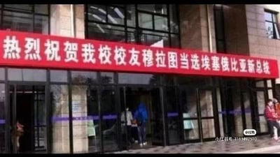 图片展示了一栋建筑物的正门，门口上方悬挂着一条红色横幅，上面写着“热烈祝贺我校校友穆拉图当选埃塞俄比亚总统”。建筑物为多层结构，玻璃幕墙设计，门口有几人正在进出或停留。画面右下角有“小红书号：115497510”的水印。
