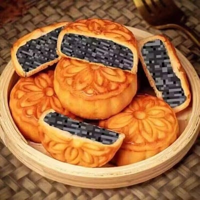 图片展示了一竹制容器中摆放的多块传统广式月饼，其中数块被切开，露出的内馅并非常见的莲蓉、豆沙等馅料，而是被修改为黑白灰相间的像素块图案，类似代码或键盘按键的样式，通过P图的方式制造出“代码馅月饼”的趣味效果，用来调侃程序员群体，将节日元素与程序员的工作元素结合，形成反差搞笑的创意。