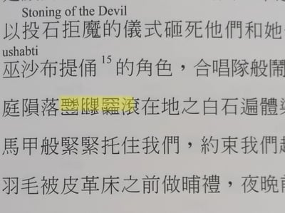 这是一张纸质印刷读物内页的翻拍静态图，页面内容为横排印刷的英文与繁体中文文本，内容涉及宗教相关的文化表述，包含“投石拒魔仪式”“巫沙布提俑”等相关词汇，其中有三个极为罕见的生僻汉字被黄色荧光笔高亮标注，其余文本为常规繁体印刷宋体字，本次仅截取了读物的部分段落内容。